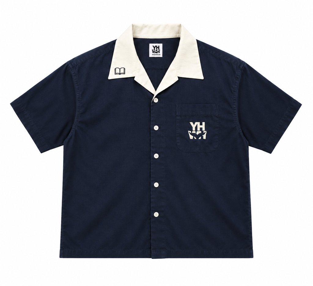 A navy blue short-sleeve camp collar button-up shirt with a cream collar, featuring a chest pocket with a white embroidered 'YHWH' logo and white buttons.