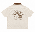 An beige short-sleeve button-up shirt shown from the back, featuring a brown collar and a brown graphic print on the back that reads 'Lamp to my feet HOLY BIBLE' with scripture references.