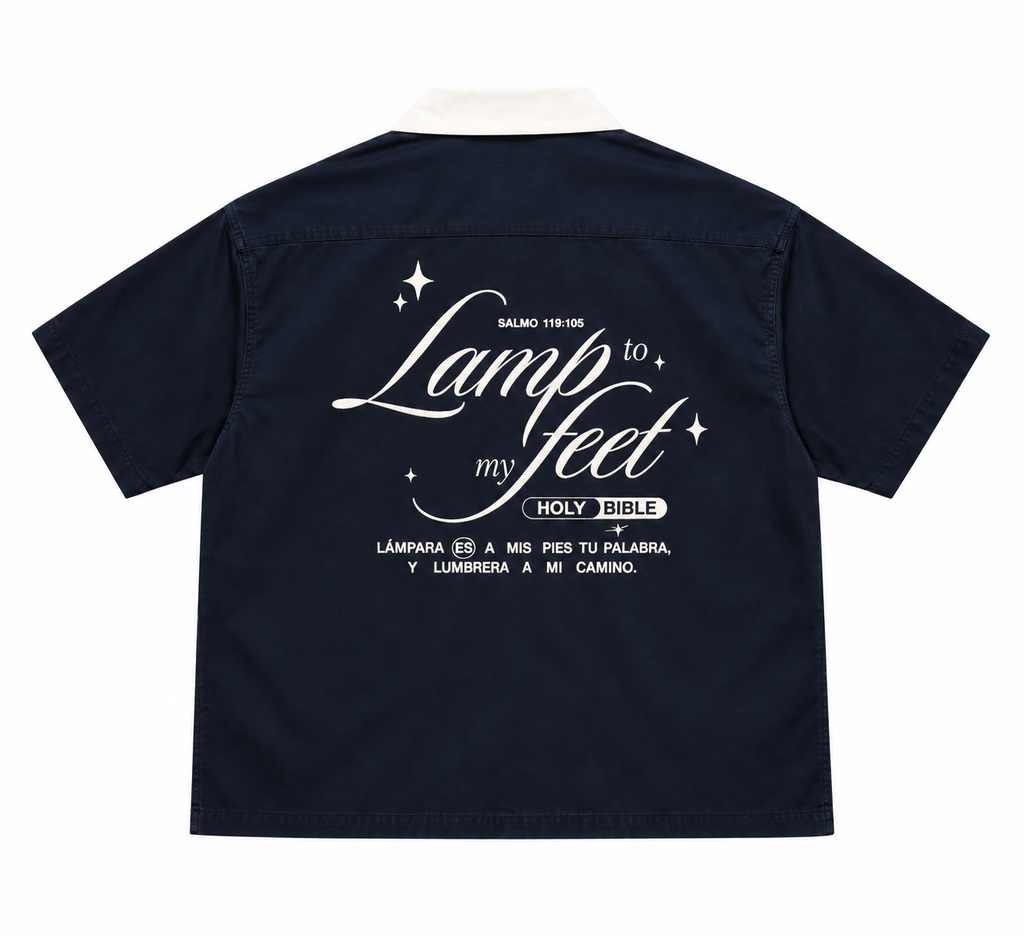 A navy blue short-sleeve shirt shown from the back, featuring a white graphic print with the words 'Lamp to my feet' and 'Holy Bible' on a plain white background.