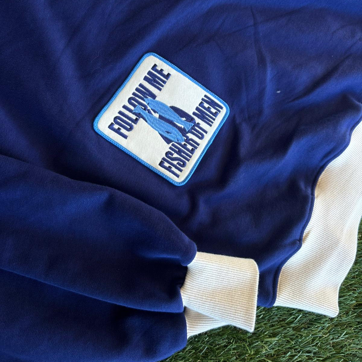 Blue jacket with a patch on a grassy background